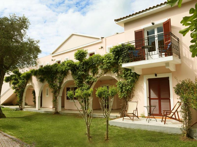 Hotel mit Balustraden, grünen Bäumen und Stühlen auf der Terrasse an einem sonnigen Tag