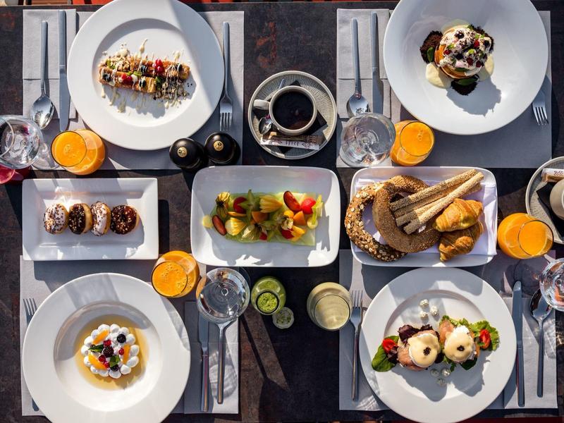 Tisch mit verschiedenen Frühstücksgerichten, Getränken und Besteck in einem Hotel.