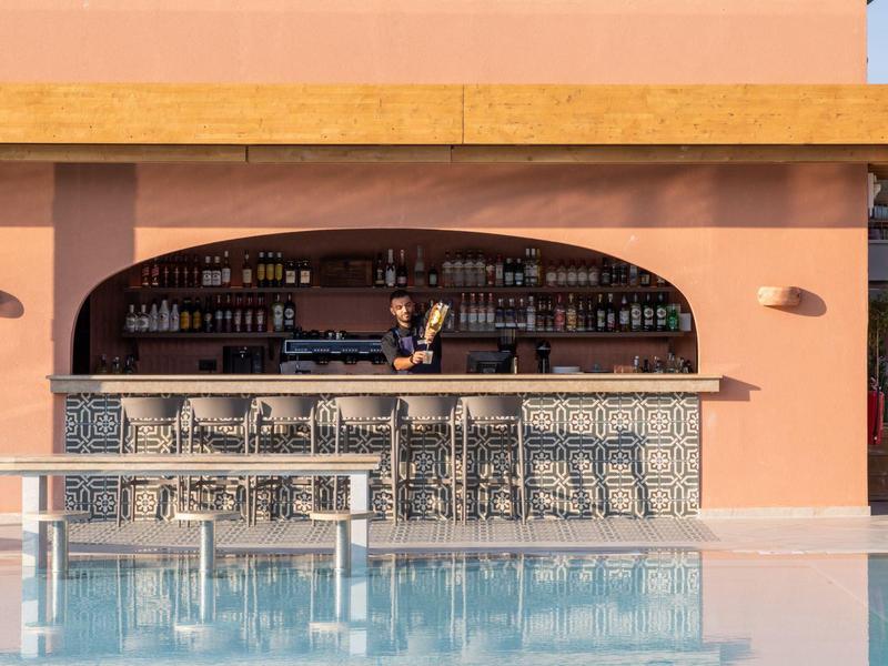 Moderne Poolbar mit steinverkleidetem Tresen und Barkeeper an einem sonnigen Tag.