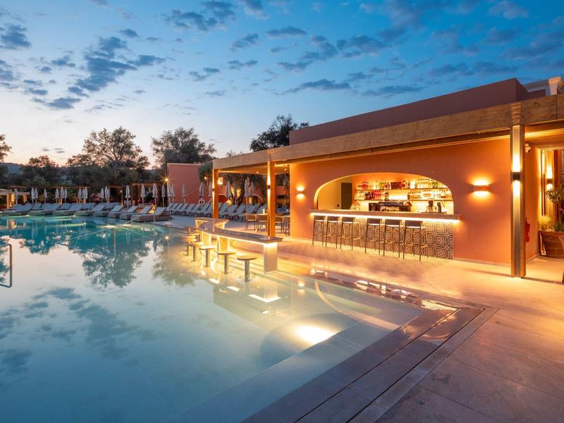 Abendliche Hotelpoolbar mit beleuchtetem Swimmingpool und Sitzgelegenheiten im Freien.
