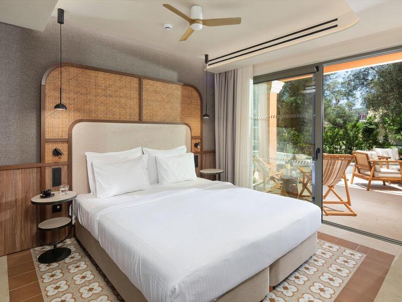 Modernes Hotelzimmer mit Doppelbett und Zugang zu einer Terrasse mit Sitzbereich