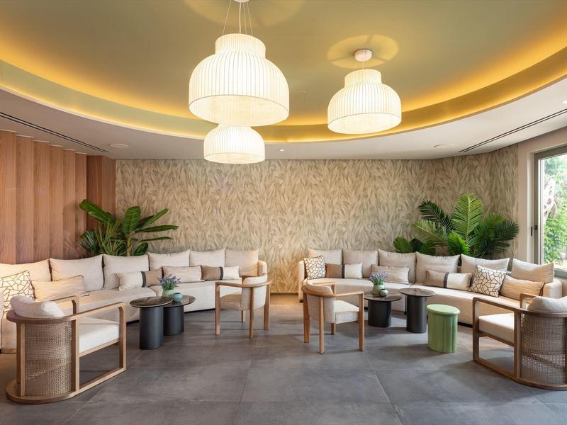 Moderner Lounge-Bereich mit bequemen Sesseln, Sofas, Steintapete und grünen Pflanzen in einem Hotel.