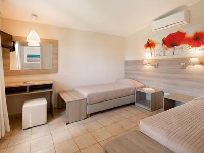 Chambre avec deux lits simples, bureau, tabouret et décoration lumineuse moderne.