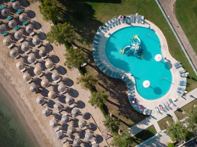 Luftaufnahme von Pool mit Wasserfontäne, Liegestühlen und Sonnenschirmen am Strand.