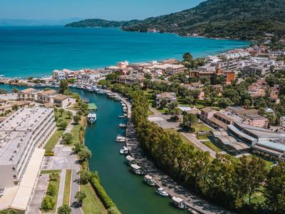 Ville côtière avec embouchure de rivière, entourée de bâtiments et de collines sous un ciel bleu.