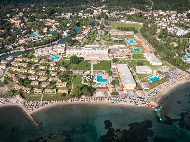 Vue aérienne d'un grand complexe avec plusieurs piscines sur la plage entourée de verdure.