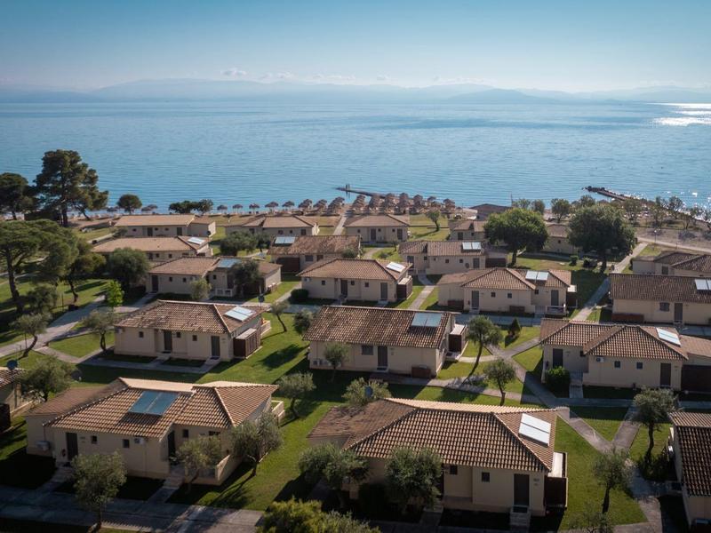 Vue d'un complexe hôtelier avec plusieurs bungalows au bord de la mer sous un ciel dégagé.