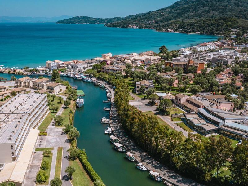 Ville côtière avec embouchure de rivière, entourée de bâtiments et de collines sous un ciel bleu.