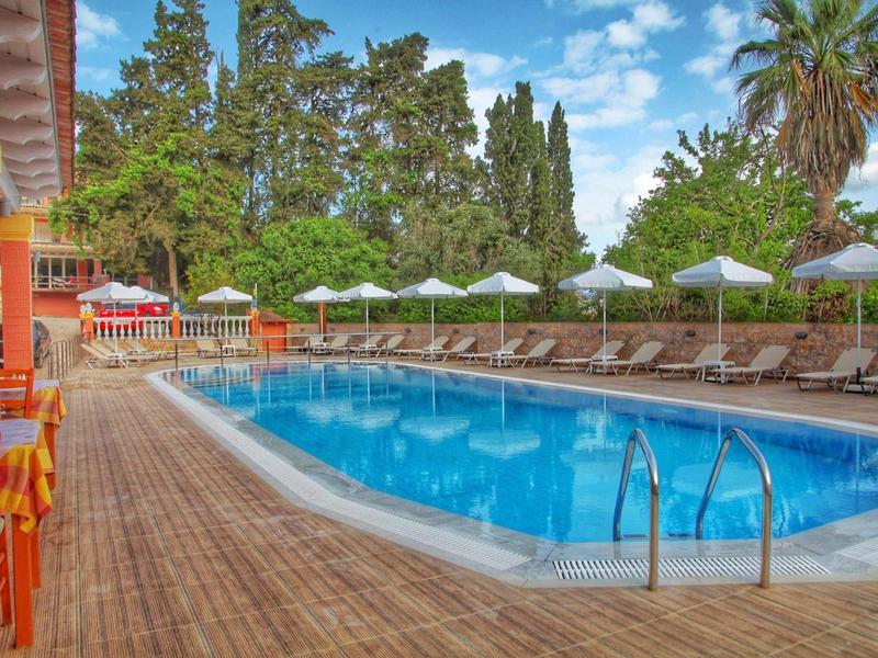 Freier Pool mit bläulichem Wasser, umgeben von Holzboden, Liegestühlen und weißen Sonnenschirmen.