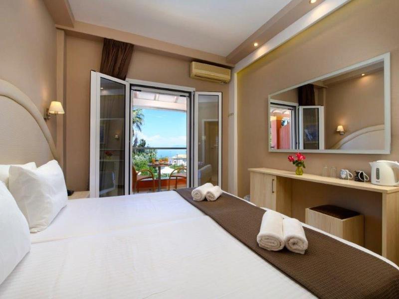 Modernes Hotelzimmer mit Doppelbett, großem Spiegel, Schreibtisch und Balkon mit Meerblick.