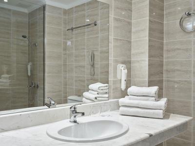 Modern bathroom with a large mirror, white sink, marble countertop, and neatly stacked towels.