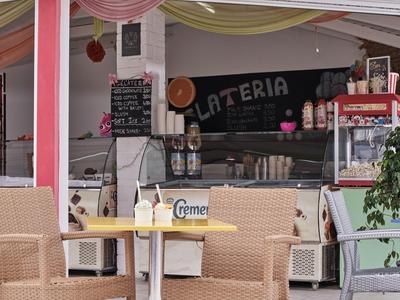 Outdoor seating area of a café with wicker chairs and a black menu board in the background