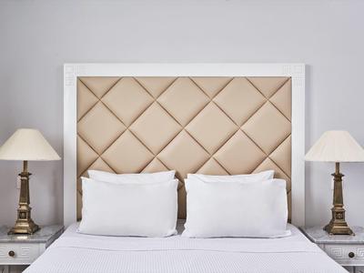 Symmetrical bedroom with two white pillows, beige tufted headboard, and brass table lamps.