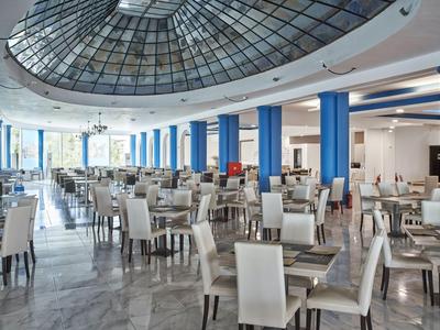 Spacious, bright dining area with white chairs, blue columns, and large glass dome.