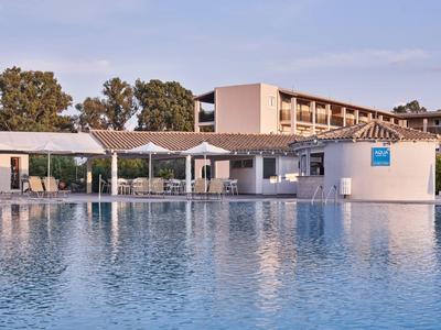 Large hotel pool with sun umbrellas and multi-story building in the background.