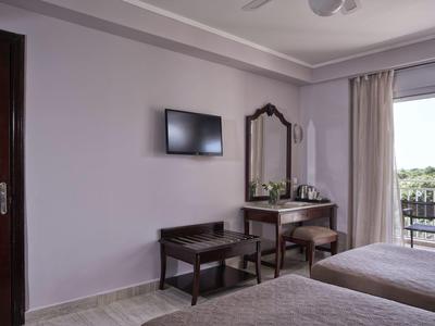 Hotel room with twin beds, a TV on the wall, a mirror, and a balcony with a view outside.