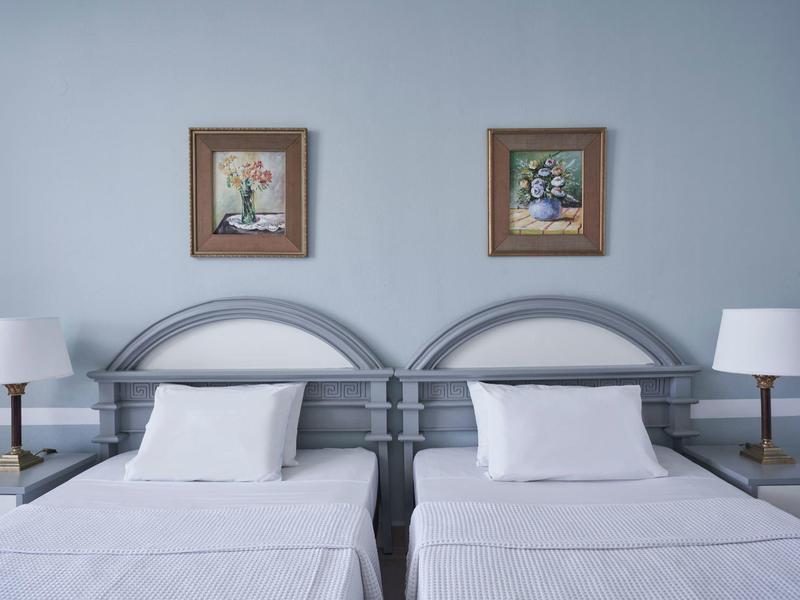 Twin beds with white linens, gray headboards, matching lamps, and wall art in a hotel room.