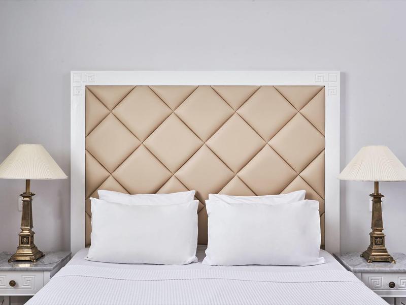 Symmetrical bedroom with two white pillows, beige tufted headboard, and brass table lamps.