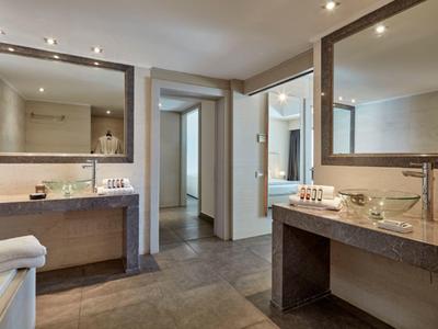 Großzügiges Badezimmer mit zwei großen Spiegeln, modernen Waschbecken und beigem Fliesenboden.