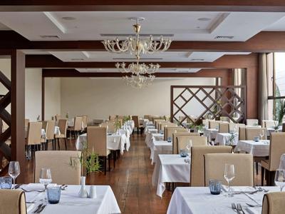 Eleganter Speisesaal mit weißen Tischdecken, Kristallleuchtern und modernem Dekor in einem Hotel.