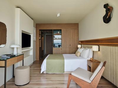 Modernes Hotelzimmer mit Doppelbett, Holzakzenten und schlichter, heller Dekoration.