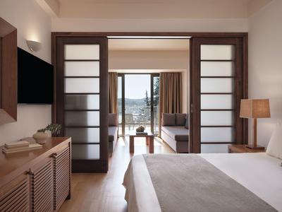Modernes Hotelzimmer mit Doppelbett, TV und Zugang zu Terrasse mit Meerblick.