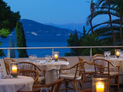 Terrassenrestaurant mit Kerzenlicht, Holzmöbeln und Blick auf einen ruhigen See und Berge.