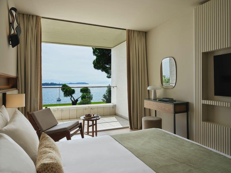 Modernes Hotelzimmer mit großen Fenstern und Blick auf das Meer und die Terrasse.