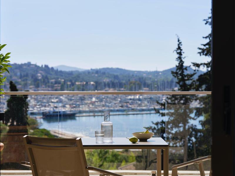 Blick von Terrasse mit Tisch, Stuhl und Meereshafen im Hintergrund.