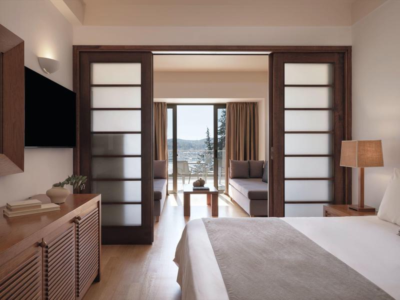 Modernes Hotelzimmer mit Doppelbett und Blick auf den Balkon mit Meerblick.