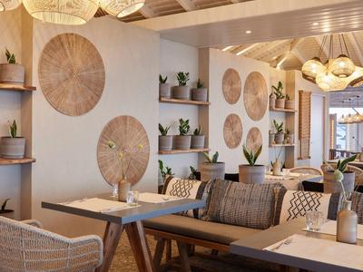 Moderner Innenraum mit Holzdecke, runden Wanddekorationen, Pflanzen und gemütlichen Sitzgelegenheiten.