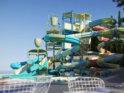 Wasserpark mit bunten Rutschen und transparenten Sitzstühlen bei klarem Himmel.