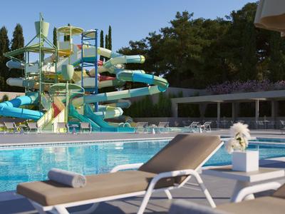 Silla de descanso vacía junto a la piscina con toboganes y cielo azul de fondo.