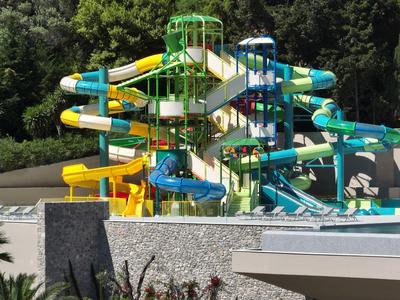 Toboganes de agua coloridos en un parque acuático con árboles verdes al fondo