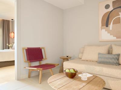 Moderner Wohnraum mit hellen Wänden, beige Couch, rundem Holztisch und rotem Stuhl.