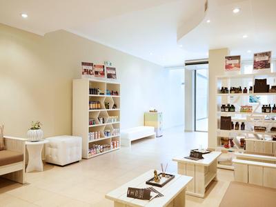 Hell eingerichteter, moderner Raum mit Bücherregalen, Sofa, Sesseln und Couchtischen.