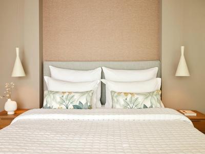 Modernes Schlafzimmer mit Doppelbett, zwei Nachttischen, beiger Wand und minimalistischer Dekoration.