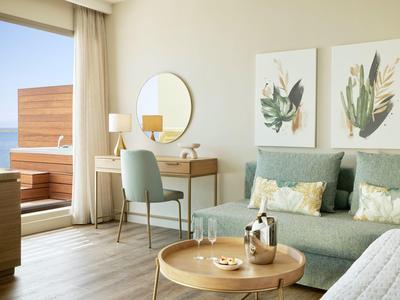 Helles Wohnzimmer mit grünem Sofa, rundem Couchtisch, Schminktisch und terrassenartigem Balkon.