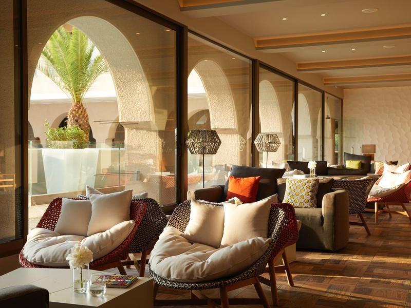 Gemütlicher Innenraum mit großen Bögen, Holzfußboden und bequemen Sesseln mit Kissen.