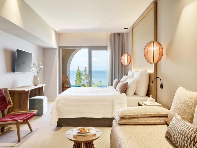 Modernes Hotelzimmer mit Doppelbett, Meerblick, Holzmöbeln und warmweißer Beleuchtung.