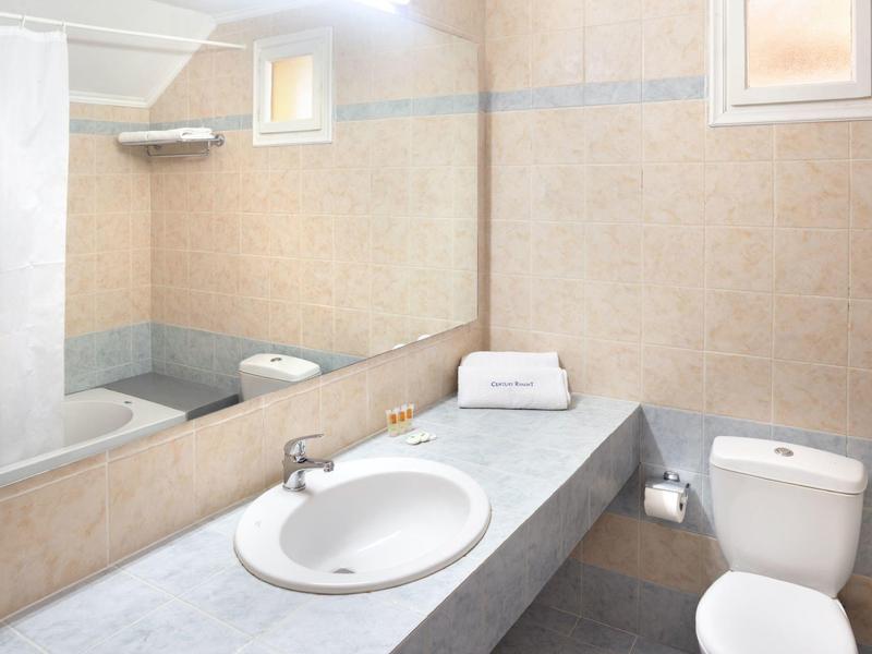 Helles Badezimmer mit großem Spiegel, rundem Waschbecken, Toilettensitz und grauer Arbeitsplatte.