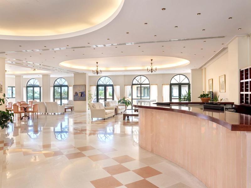 Heller, großer Empfangsbereich mit geschwungenem Tresen, großen Fenstern und elegantem Deckenlicht.
