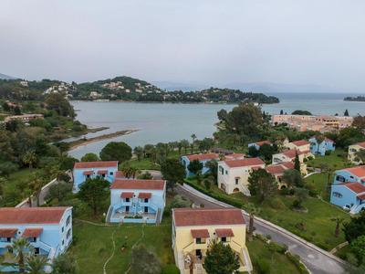 Vista de un paisaje costero con casas azules y rojas a lo largo de una carretera y el mar al fondo.