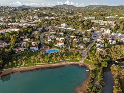 Küstenstadt mit vielen Häusern, grünem Park, blauem Schwimmbecken und Flussmündung ins Meer.