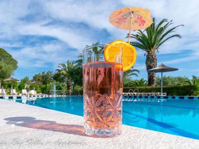 Bebida refrescante con naranja en el borde de una piscina en un día soleado.