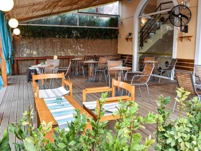 Acogedora terraza de restaurante con sillas y mesas de madera, rodeada de plantas.
