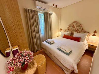 Bright hotel room with double bed, beige wall decoration, and window with curtains.