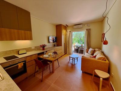 Cozy living room with sofa, TV, dining area, and access to a terrace with green view.