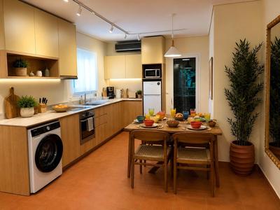Modern hotel kitchen with wooden cabinets, dining area, and washing machine.