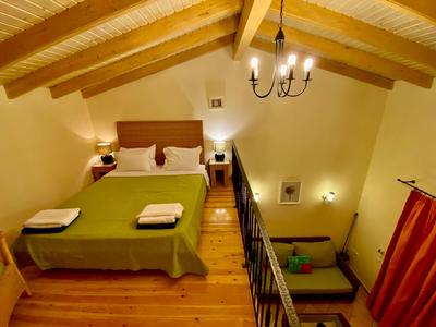 Cozy hotel room with wooden beam ceiling, double bed, and stairs leading to a comfortable seating area.